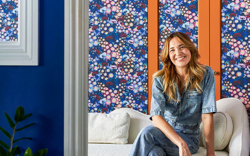 Jo Jackson in a room decorated in Lick floral wallpaper and orange paint