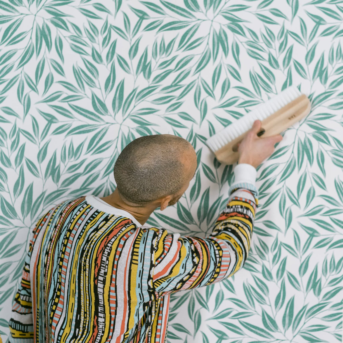 Man smoothing Lick Botanical 03 Wallpaper onto a wall
